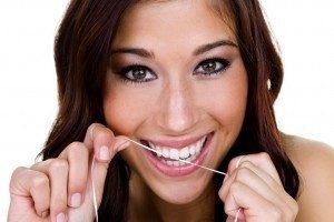 Woman flossing confidently, knowing her dental crown is secure. 